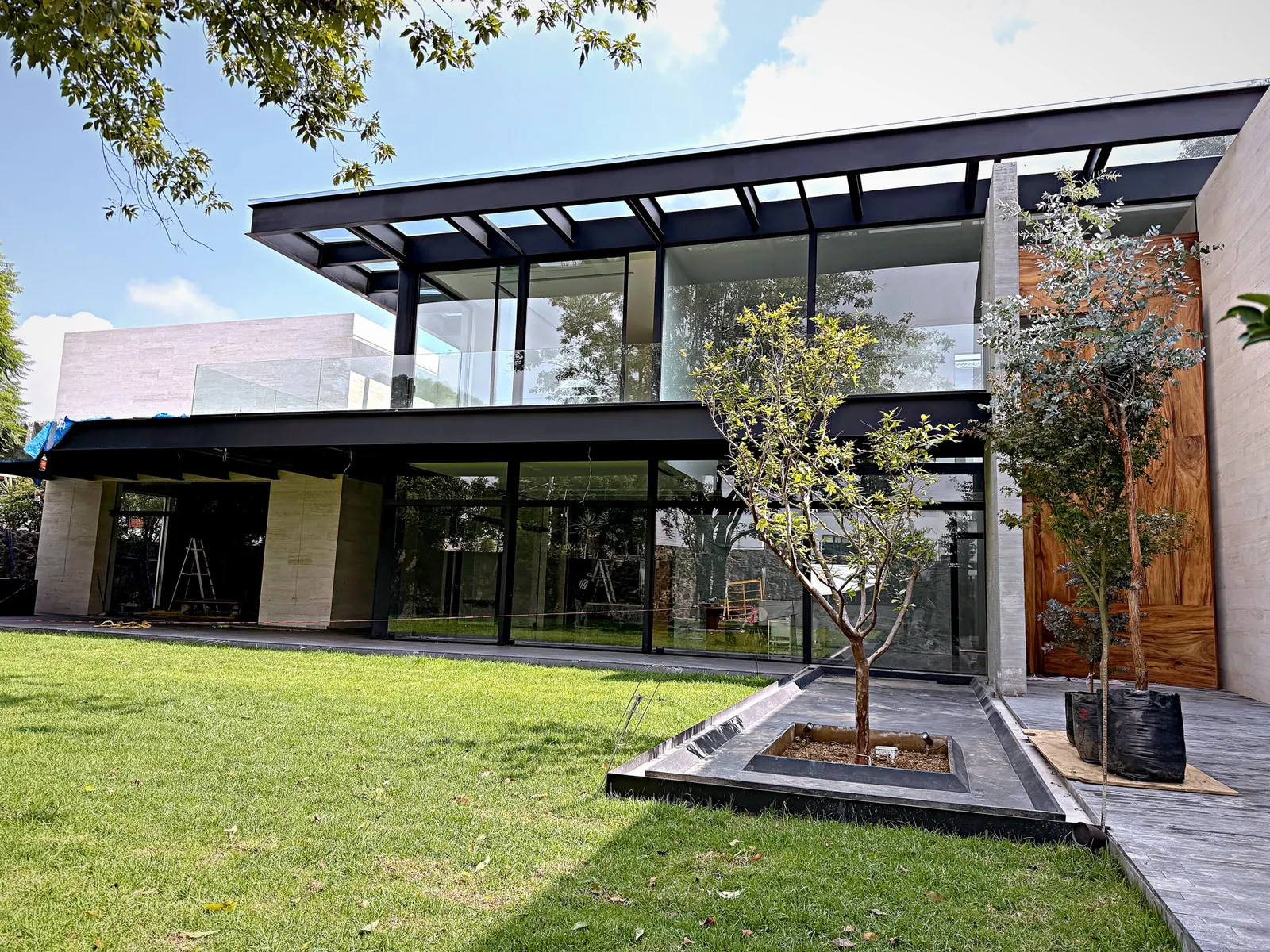 Casa con ventanales de aluminio negro y barandal de vidrio en planta alta