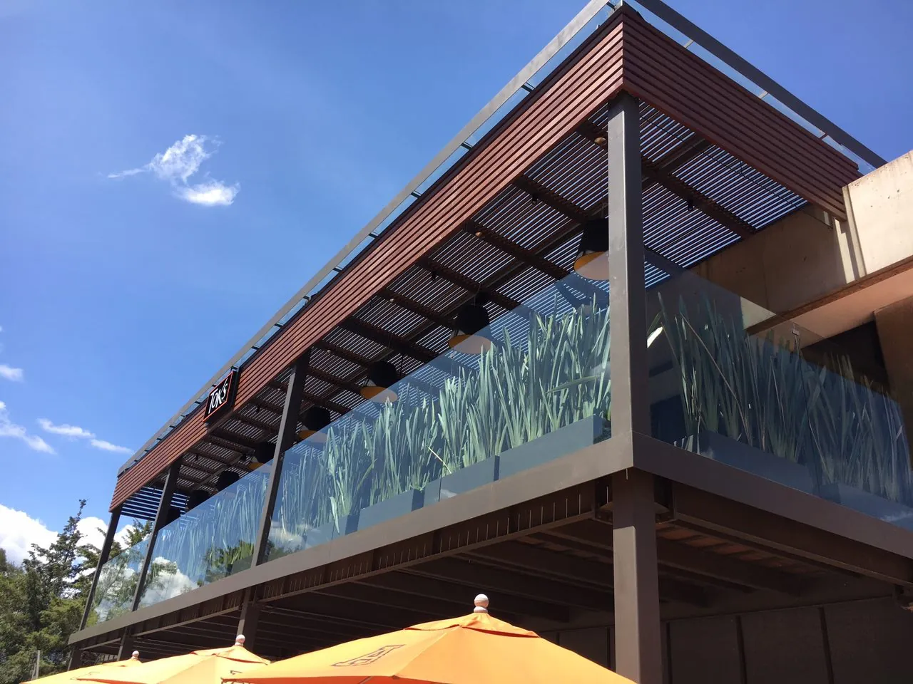 Terraza de Restaurantes Toks con celosía de madera y cristales con jardineras